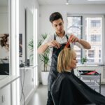 Парикмахер стрижет клиента в светлом современном салоне